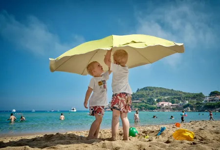 2 kinderen onder parasol op het strand